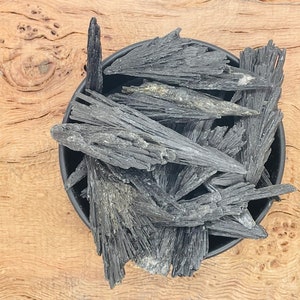 May include: A black bowl filled with black and grey, naturally occurring, pointed, crystal-like mineral shards.