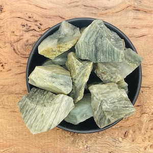 May include: A bowl filled with green and white striped stones. The stones are rough and have a natural, unpolished look.