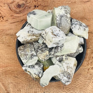 May include: A bowl of white and green speckled stones. The stones are smooth and have a natural, organic look.