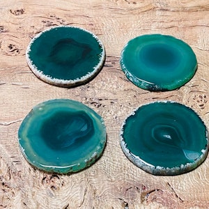 May include: Four green agate coasters with white edges. The coasters are round and have a natural, polished finish.
