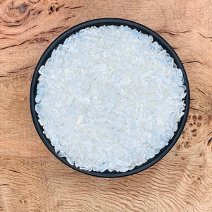 May include: A black bowl filled with small, white, translucent, iridescent, crystal chips.