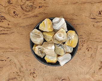 May include: A bowl of yellow and white agate stones. The stones are rough and have a natural, organic shape.
