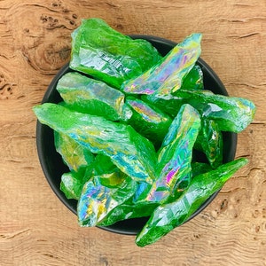 May include: A bowl filled with green iridescent crystal points. The crystals are sharp and have a rainbow sheen.