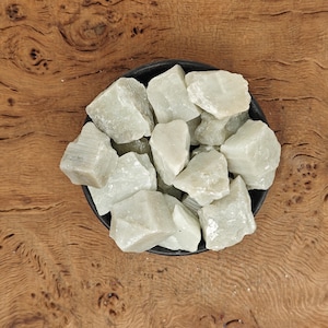 May include: A bowl filled with a collection of white and green gemstone chips. The chips are rough and have a natural, unpolished look.