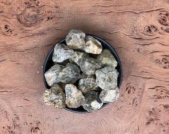 May include: A close-up of a bowl filled with small, light gray and green rocks. The rocks are smooth and have a natural, earthy look.