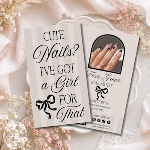 May include: Two rectangular business cards with a light beige striped background. The left card features the black text CUTE Nails? I'VE GOT a Girl FOR THAT and a bow icon. The right card shows a photo of manicured nails and Fern Green NAIL ARTIST.
