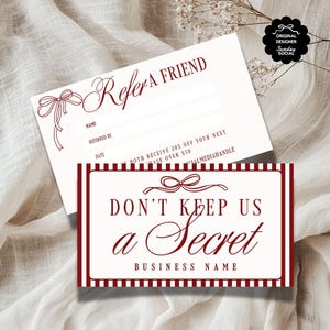 Pode incluir: Dois cartões de referência creme com texto bordô e ilustrações de laços. Um cartão diz "Indique um amigo" com campos para nome e data. O outro diz "Não nos guarde em segredo" com um campo para o nome da empresa. Os cartões estão em um tecido branco.