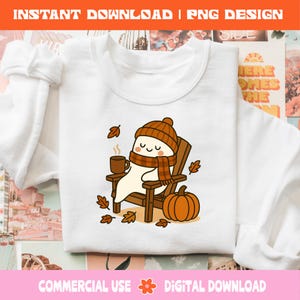 Pode incluir: Camisola branca com um fantasma de desenho animado usando um chap&eacute;u e cachecol marrons, sentado em uma cadeira de madeira, segurando uma caneca de caf&eacute; e cercado por folhas de outono e uma ab&oacute;bora. O texto na parte superior diz "INSTANT DOWNLOAD | PNG DESIGN".