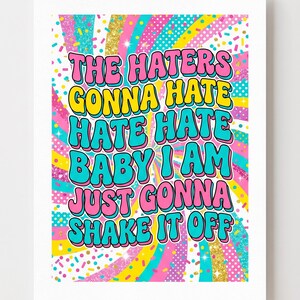 以下が含まれることがあります： 「THE HATERS GONNA HATE HATE HATE BABY I AM JUST GONNA SHAKE IT OFF」の文字がバブルレターで書かれたカラフルなプリント。背景には、紙吹雪とキラキラのアクセントが付いた虹のデザインがあります。