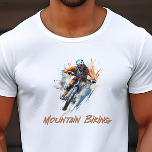 May include: White t-shirt with a watercolor illustration of a person mountain biking. The text "Mountain Biking" is printed in orange below the illustration.