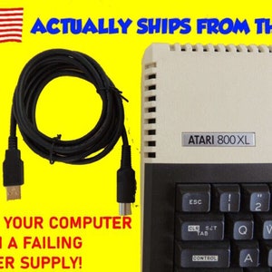 May include: A black cable with a DB-9 connector on one end and a 4-pin DIN connector on the other end. The cable is coiled and is next to a white Atari 800XL computer. The text "ATARI 800XL" is on the computer. The text "SAVE YOUR COMPUTER FROM A FAILING POWER SUPPLY!" is on a yellow background.