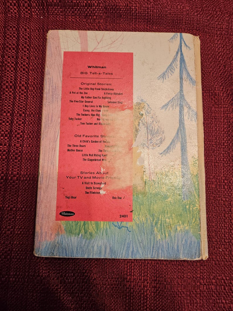 Op de afbeelding: Vintage Whitman "Big Tell-a-Tales" boek. De omslag toont een grillige illustratie van een bossc&egrave;ne met bomen en gras. De titel van het boek en een lijst met verhalen zijn zichtbaar.