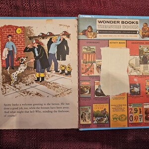 May include: An open book with a colorful illustration of a dalmatian dog barking at three firefighters. The book is open to a page with text about the dog minding the firehouse. The back cover of the book features a selection of Wonder Books, including storybooks, activity books, and educational books.
