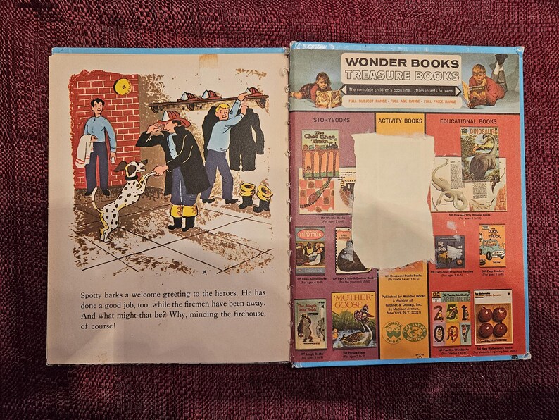 May include: An open book with a colorful illustration of a dalmatian dog barking at three firefighters. The book is open to a page with text about the dog minding the firehouse. The back cover of the book features a selection of Wonder Books, including storybooks, activity books, and educational books.