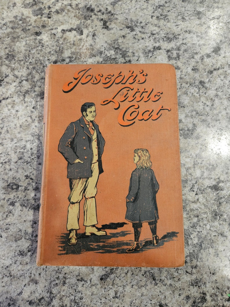 Puede incluir: Un libro naranja con el t&iacute;tulo "Joseph's Little Coat" en letras cursivas negras. La portada presenta una ilustraci&oacute;n de un hombre y un ni&ntilde;o con ropa de &eacute;poca.