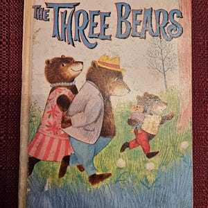 Op de afbeelding: Vintage kinderboek getiteld "The Three Bears" van Whitman. De omslag toont een illustratie van drie beren in een kleurrijke buitensc&egrave;ne. De titel staat in grote, blauwe, gestileerde letters.