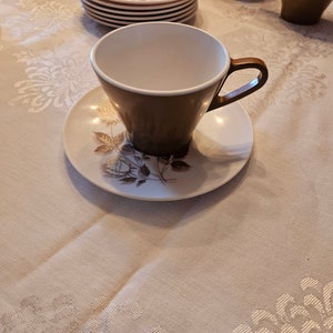 Op de afbeelding: Een set van drie keramische mokken met een gespikkelde, matte afwerking. De mokken zijn in tinten crème, lichtbruin en donkerbruin. Elke mok heeft een eenvoudig, minimalistisch ontwerp.