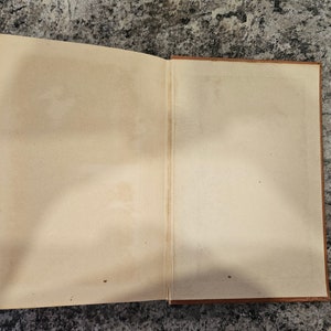 Puede incluir: Un libro abierto con p&aacute;ginas en blanco. El libro tiene una cubierta de cuero marr&oacute;n.