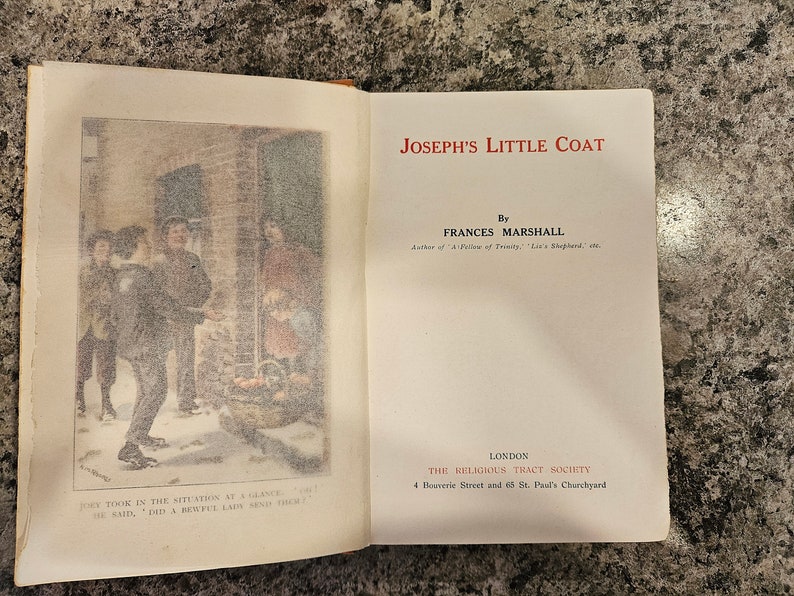 Puede incluir: Un libro antiguo titulado "Joseph's Little Coat" de Frances Marshall. La portada del libro presenta una ilustraci&oacute;n en blanco y negro de personas en una escena de calle nevada. El libro fue publicado por The Religious Tract Society en Londres.