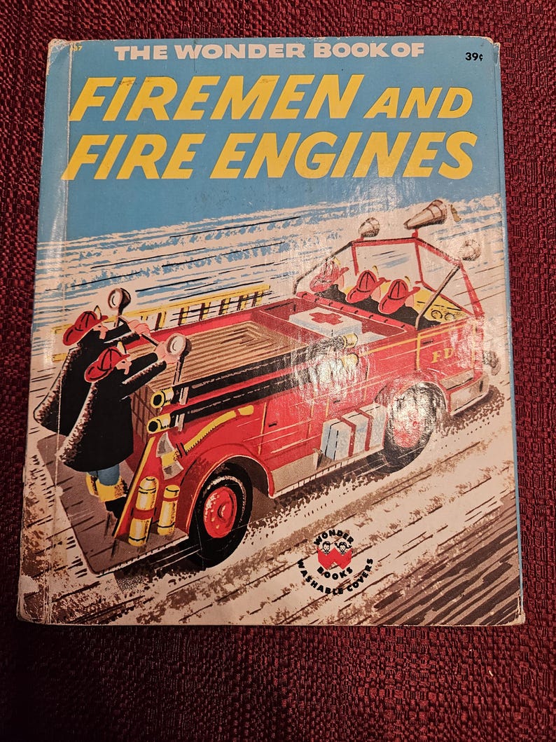May include: A vintage children's book cover featuring a red fire engine with firefighters rushing to a scene. The book is titled "The Wonder Book of Firemen and Fire Engines" and has a price of 39 cents.