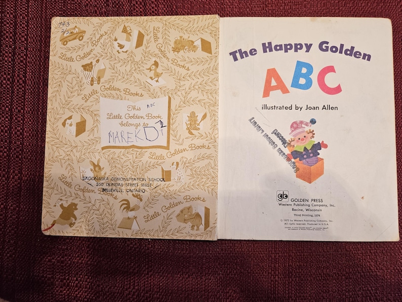 May include: A vintage children's book titled "The Happy Golden ABC" illustrated by Joan Allen. The cover features a colorful illustration of the letters A, B, and C, and a child in a red and white hat peeking out of a box.