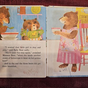 Op de afbeelding: Illustratie uit een vintage kinderboek met drie beren die ontbijten. E&eacute;n beer serveert eten, een ander eet en een derde zit op een stoel. De tekst luidt: "Ik wilde dat dat kleine meisje bleef spelen."