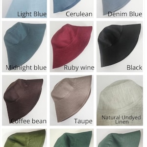 May include: A grid of twelve bucket hats in various colors labeled Light Blue, Cerulean, Denim Blue, Midnight Blue, Ruby Wine, Black, Coffee Bean, Taupe, Natural Undyed Linen, Cupress, Pine Grove, and Sage Green, each with a wide brim.
