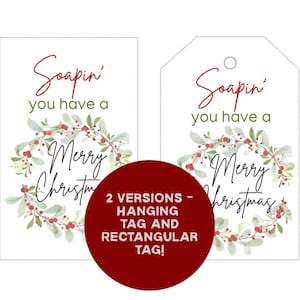May include: Two white Christmas gift tags with the text "Soapin' you have a Merry Christmas" in red and black script, surrounded by a green and red wreath. One tag is rectangular, the other has a hole for hanging.