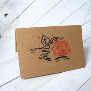 Carte de voeux estampée et sculptée à la main d'une rose sur une table