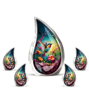 May include: Five teardrop-shaped pendants featuring a colourful hummingbird design. The pendants depict a hummingbird amidst flowers and foliage, set against a teal and purple background, within a silver-toned metal frame.