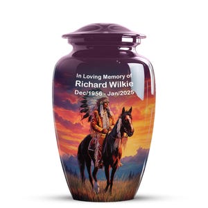 May include: A glossy, purple cremation urn with a lid. The urn features a sunset scene with a Native American on horseback. Text reads "In Loving Memory of Richard Wilkie Dec/1956 - Jan/2025."