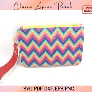 May include: A rectangular zipper pouch featuring a vibrant multi-colored chevron pattern in shades of pink, blue, yellow, and purple. The pouch has a bright yellow zipper closure and a red textured wrist strap attached to a silver metal ring.