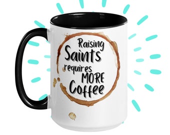 May include: White ceramic coffee mug with a black rim and handle. The mug has a brown coffee stain ring with the text "Raising Saints requires more coffee" in black.