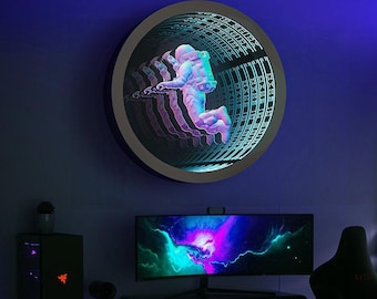 May include: A circular wall-mounted infinity mirror featuring a central graphic of an astronaut floating in space. The design creates a repeating tunnel effect with blue and purple LED lighting, showcasing a depth illusion of the astronaut figure.