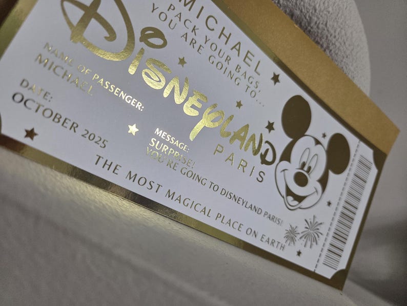 May include: A gold and white Disneyland Paris ticket with the name "MICHAEL" and the date "OCTOBER 2025". The ticket features the Disneyland logo, Mickey Mouse, and the phrase "THE MOST MAGICAL PLACE ON EARTH."