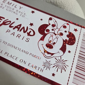 May include: A white ticket with red accents and glitter, featuring the text "Disneyland Paris" and a Minnie Mouse illustration. The ticket includes the text "Pack your bags, you are going to..." and "Magical place on Earth."