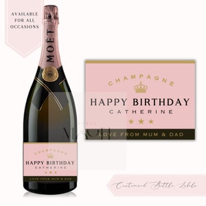 May include: Pink champagne bottle label with gold accents. The label says "Champagne Happy Birthday Catherine Love from Mum & Dad".