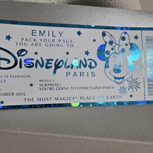May include: A Disneyland Paris ticket-themed card with a blue and silver design. The card features the Disneyland logo, Minnie Mouse, and text that reads "EMILY, PACK YOUR BAGS, YOU ARE GOING TO...DISNEYLAND PARIS".