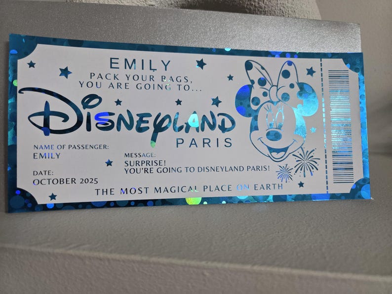 May include: A Disneyland Paris ticket-themed card with a blue and silver design. The card features the Disneyland logo, Minnie Mouse, and text that reads "EMILY, PACK YOUR BAGS, YOU ARE GOING TO...DISNEYLAND PARIS".