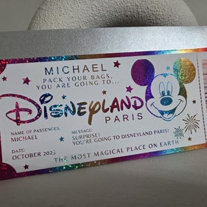 May include: A Disneyland Paris ticket with a holographic design. The ticket features the name "MICHAEL", the Disneyland logo, and Mickey Mouse. The text reads "PACK YOUR BAGS, YOU ARE GOING TO..." and "OCTOBER 2025".