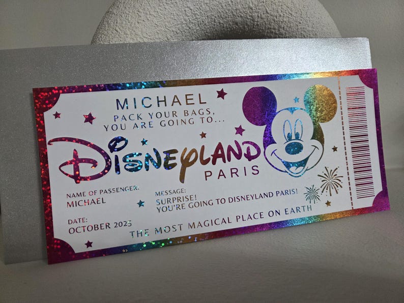 May include: A Disneyland Paris ticket with a holographic design. The ticket features the name "MICHAEL", the Disneyland logo, and Mickey Mouse. The text reads "PACK YOUR BAGS, YOU ARE GOING TO..." and "OCTOBER 2025".
