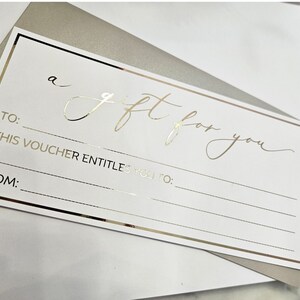 May include: A white gift certificate with gold lettering that reads "a gift for you". The certificate has lines for the recipient's name, the giver's name, and the gift details.