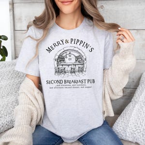 May include: A gray t-shirt with a black and white illustration of a pub with the text "Merry & Pippin's Second Breakfast Pub...and elevenses, and luncheon, and afternoon tea, and dinner, and supper".