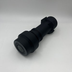 May include: A black plastic connector with a round end and a hexagonal end.