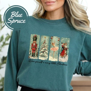 May include: Teal blue long-sleeved sweatshirt with a vintage Christmas scene featuring a nutcracker, a Christmas tree, a ballerina, and a reindeer. The text "Have yourself a merry little Christmas" is printed below the scene.