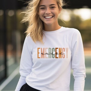 May include: White long-sleeve shirt with the text "EMERGENCY nurse" printed in colorful letters.
