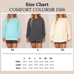May include: Size chart for a sweatshirt in sizes S, M, L, XL, 2XL, and 3XL. The chart shows the width, length, and sleeve measurements in inches for each size. The model typically wears a medium for a fitted style and an extra large for an oversized fit. She weighs 145 pounds and is 5'8" tall.