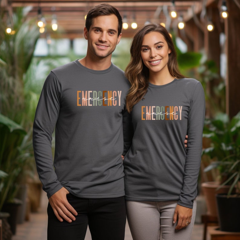 May include: Two people wearing long-sleeved shirts with the text "EMERGENCY" printed in colorful letters. The shirts are a dark charcoal grey color.