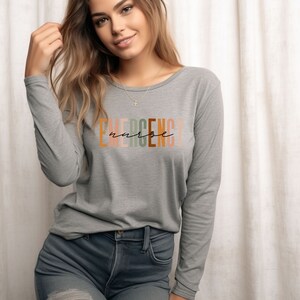May include: A gray long-sleeved shirt with the text "EMERGENCY nurse" printed in colorful letters.