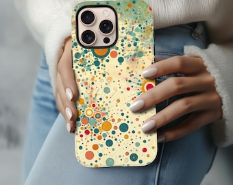 以下が含まれることがあります： カラフルな抽象デザインのスマートフォンケース。ケースは、黄色、オレンジ、ティール、赤の色合いの円と点のパターンを特徴としています。ケースにはカメラの切り抜きがあり、人の手に持たれています。